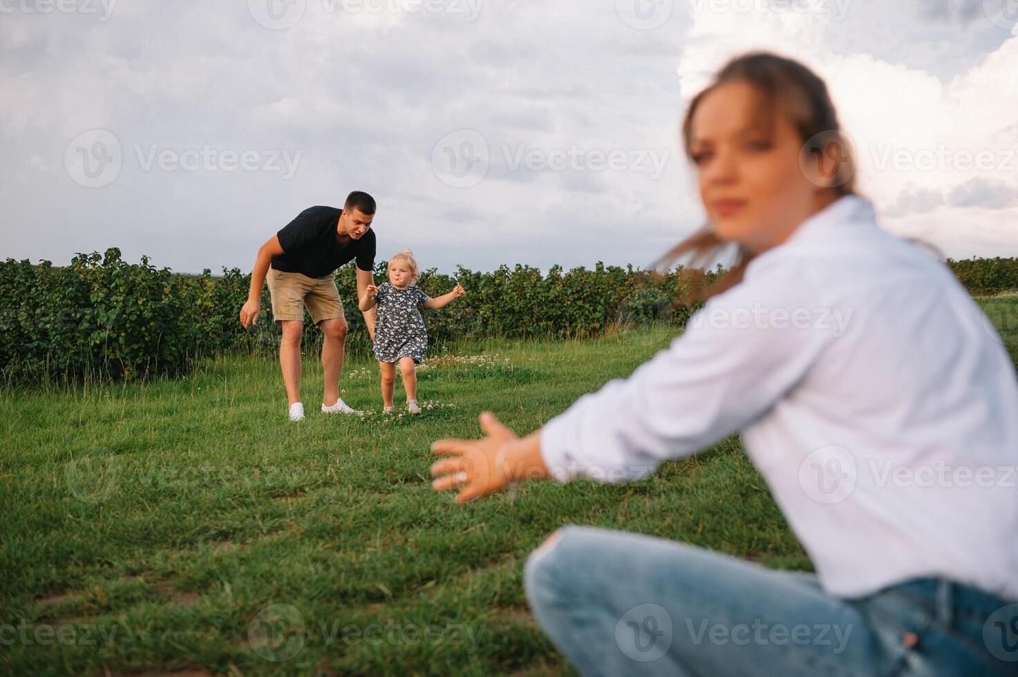 Happy family walking in the park. Mom, dad and daughter walk outdoors, parents holding the baby girl's hands. Childhood, parenthood, family bonds, marriage concept. photo