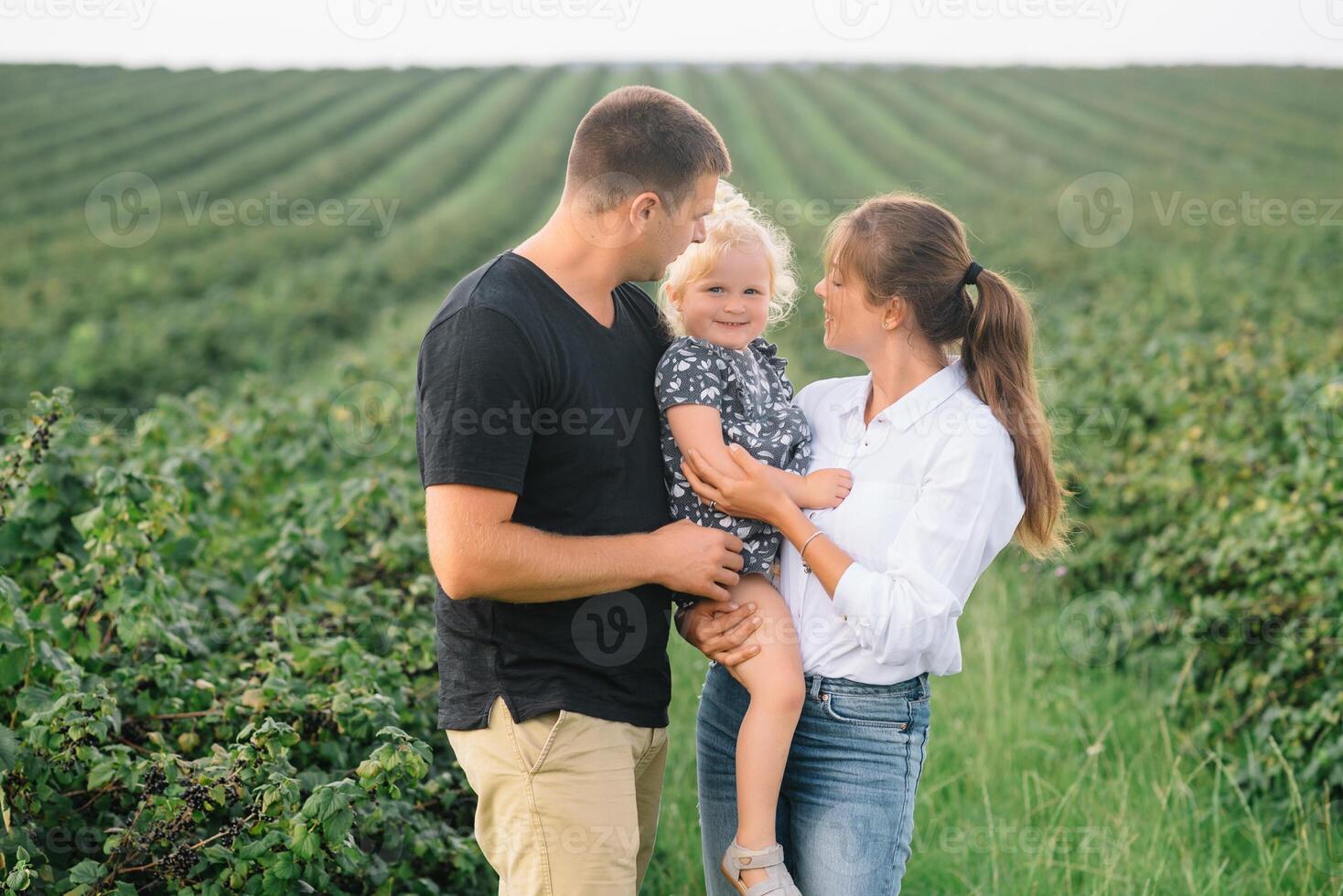 contento familia con pequeño hija gasto hora juntos en soleado campo foto