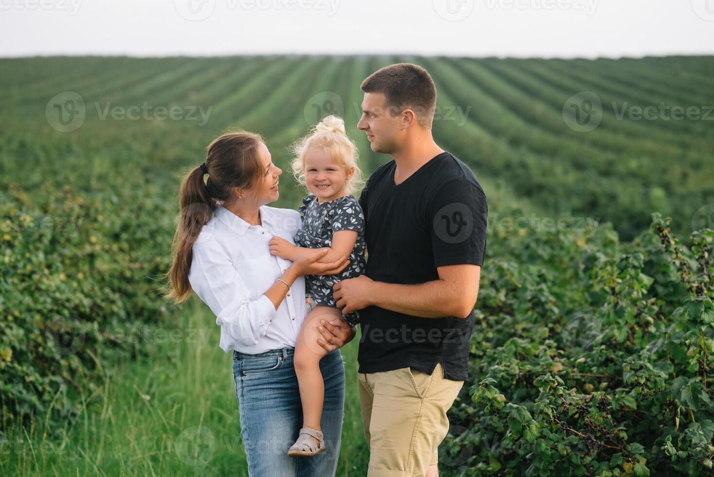 contento familia con pequeño hija gasto hora juntos en soleado campo. foto