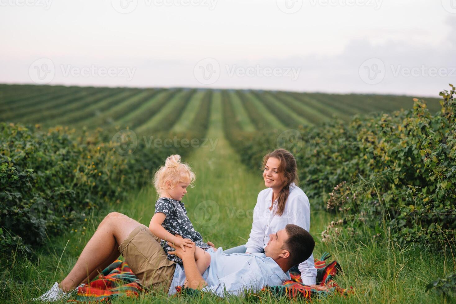 contento familia con pequeño hija gasto hora juntos en soleado campo. foto