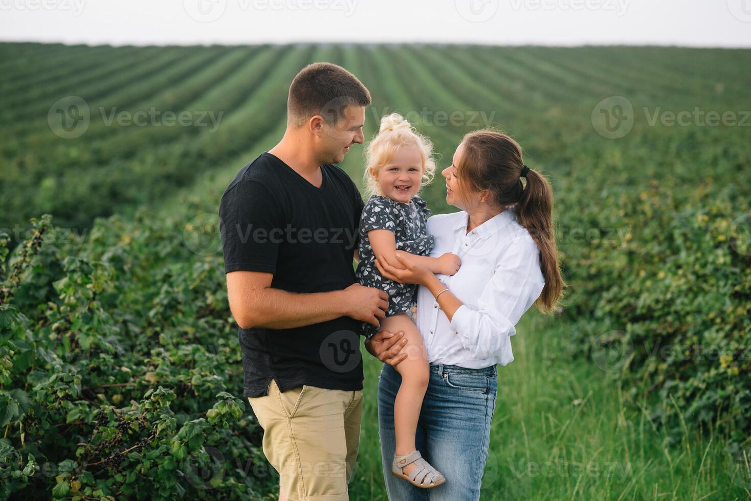 contento familia con pequeño hija gasto hora juntos en soleado campo foto