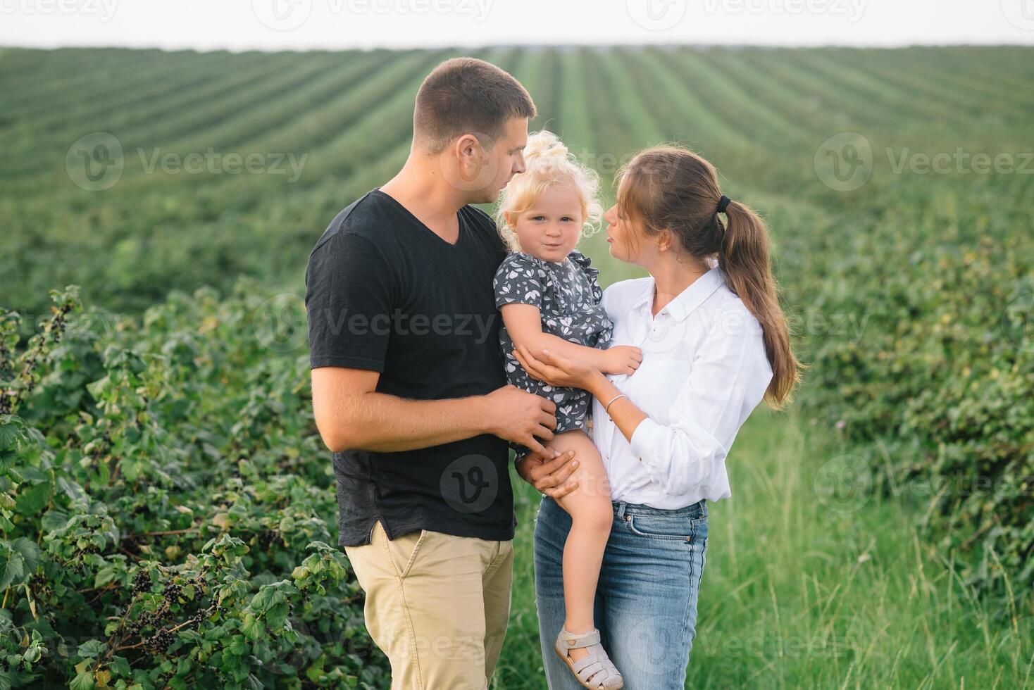 contento familia con pequeño hija gasto hora juntos en soleado campo foto