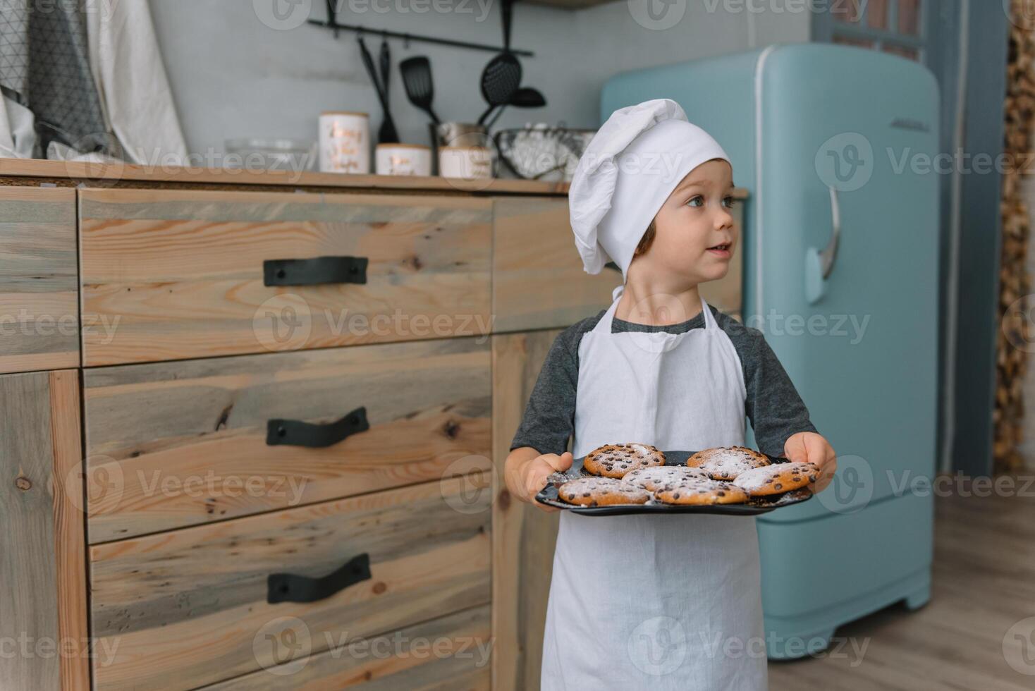 Young happy mom and her baby cook cookies at home in the kitchen. Christmas Homemade Gingerbread. cute boy with mother in white uniform and hat cooked chocolate cookies photo