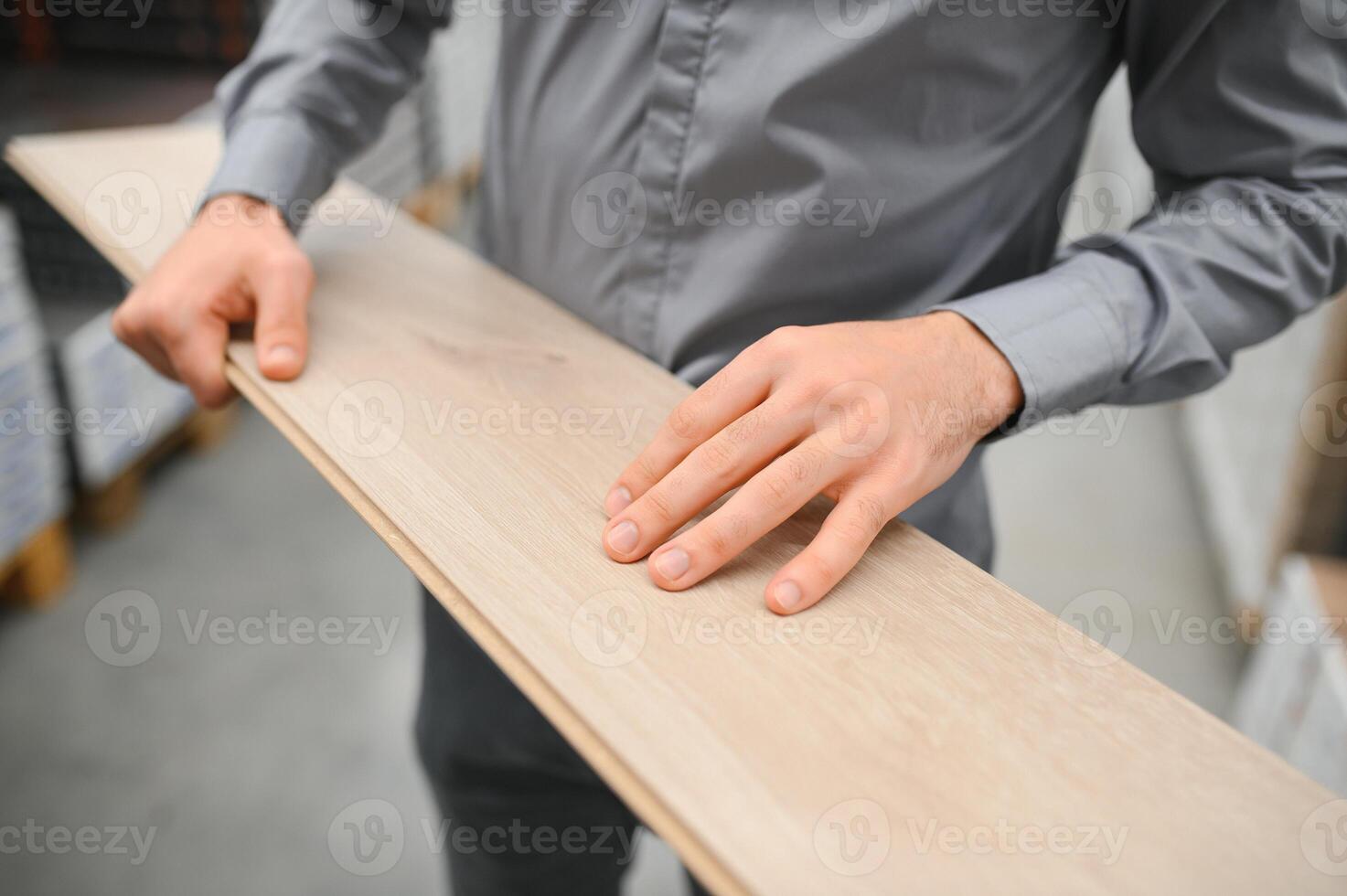 A young man chooses laminate flooring in the hardware store photo