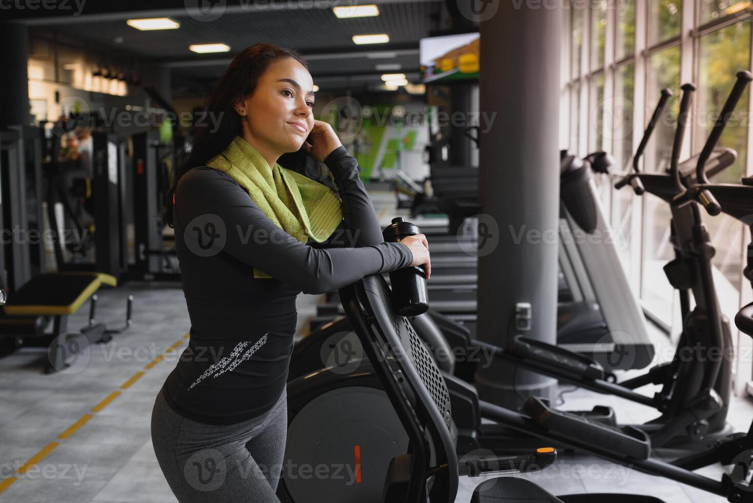 Young woman drinking water and taking a break after workout in gym photo