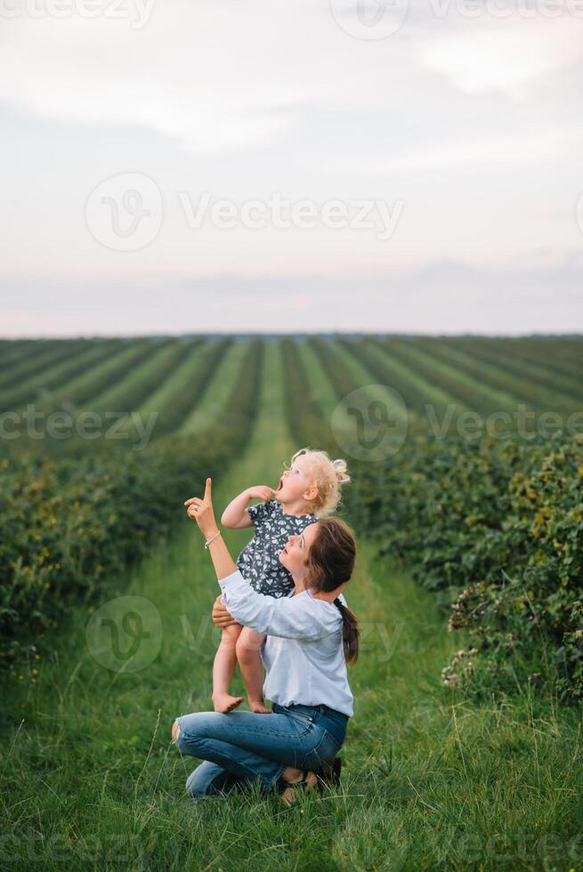 elegante madre y hija teniendo divertido en el naturaleza. contento familia concepto. belleza naturaleza escena con familia al aire libre estilo de vida. contento familia descansando juntos. felicidad en familia vida. madres día foto