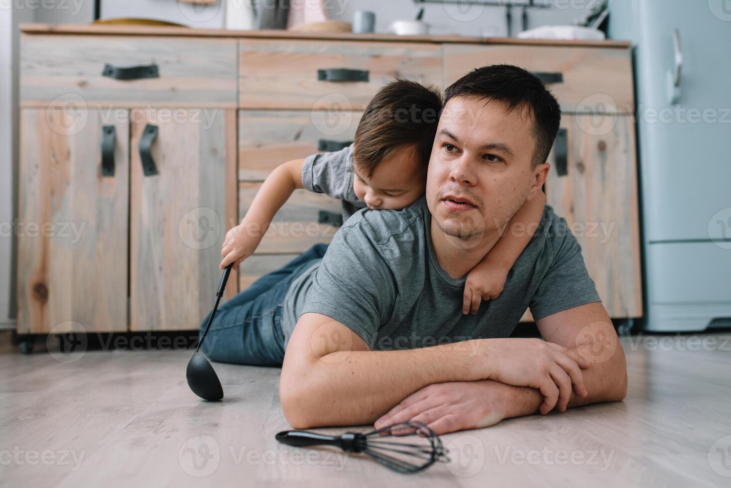 Young man and his son with oven sheet in kitchen. Father with little son on the kitchen photo