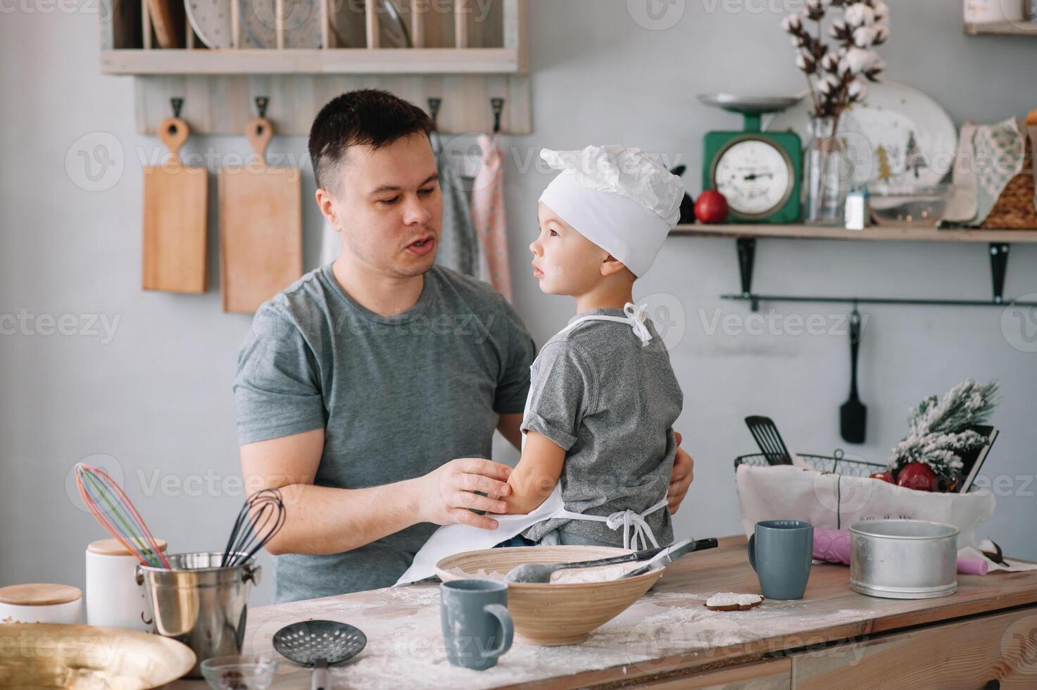 Young man and his son with oven sheet in kitchen. Father with little son on the kitchen photo