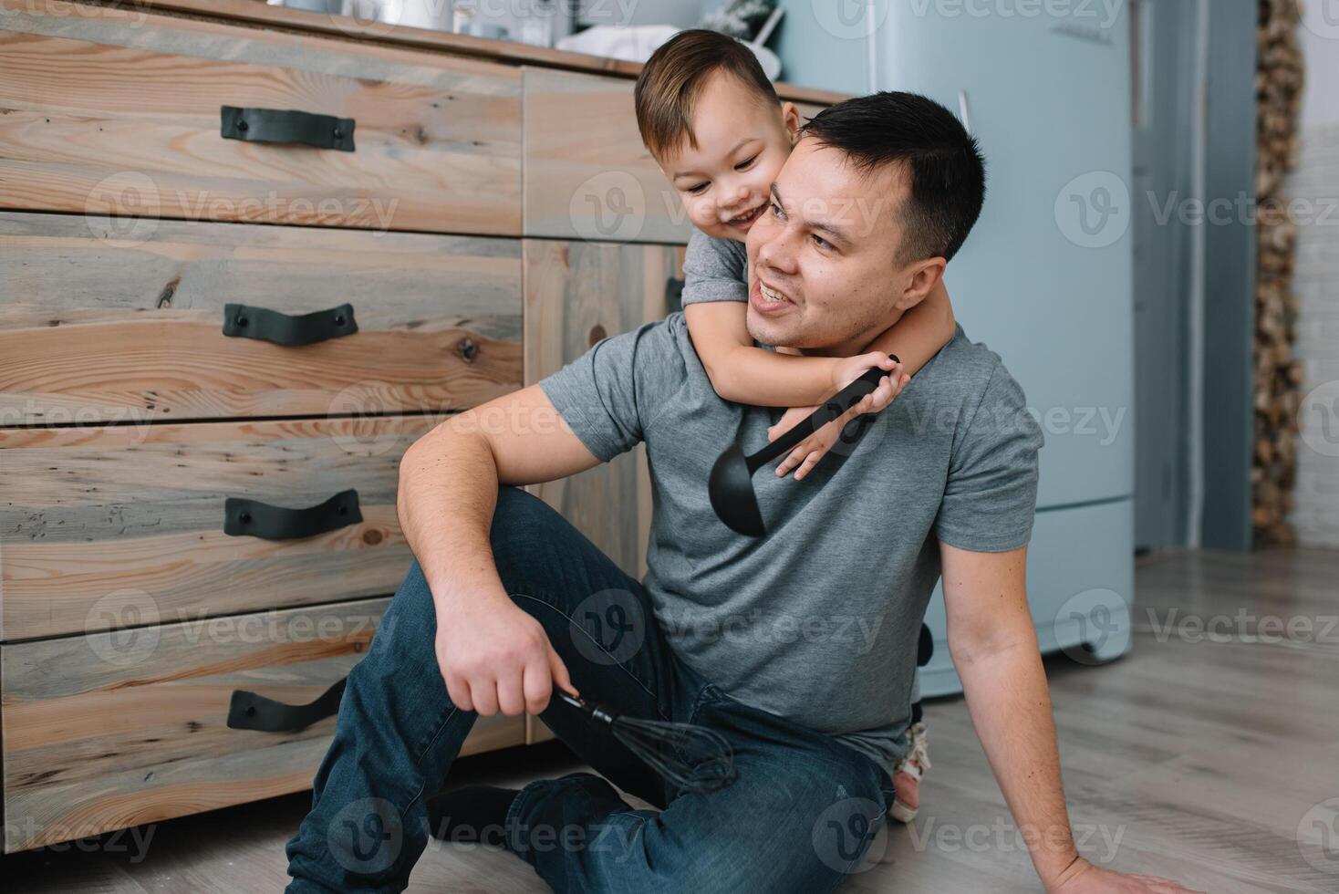Young man and his son with oven sheet in kitchen. Father with little son on the kitchen photo
