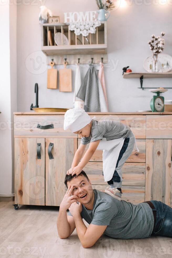 Young man and his son with oven sheet in kitchen. Father with little son on the kitchen photo