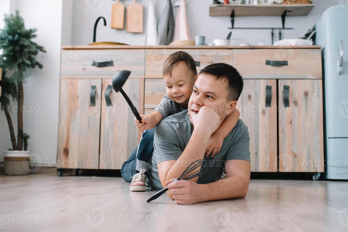Young man and his son with oven sheet in kitchen. Father with little son on the kitchen photo