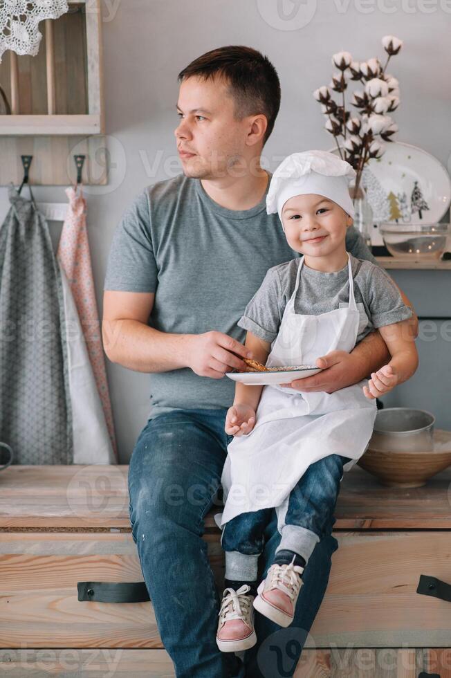 Young man and his son with oven sheet in kitchen. Father with little son on the kitchen photo