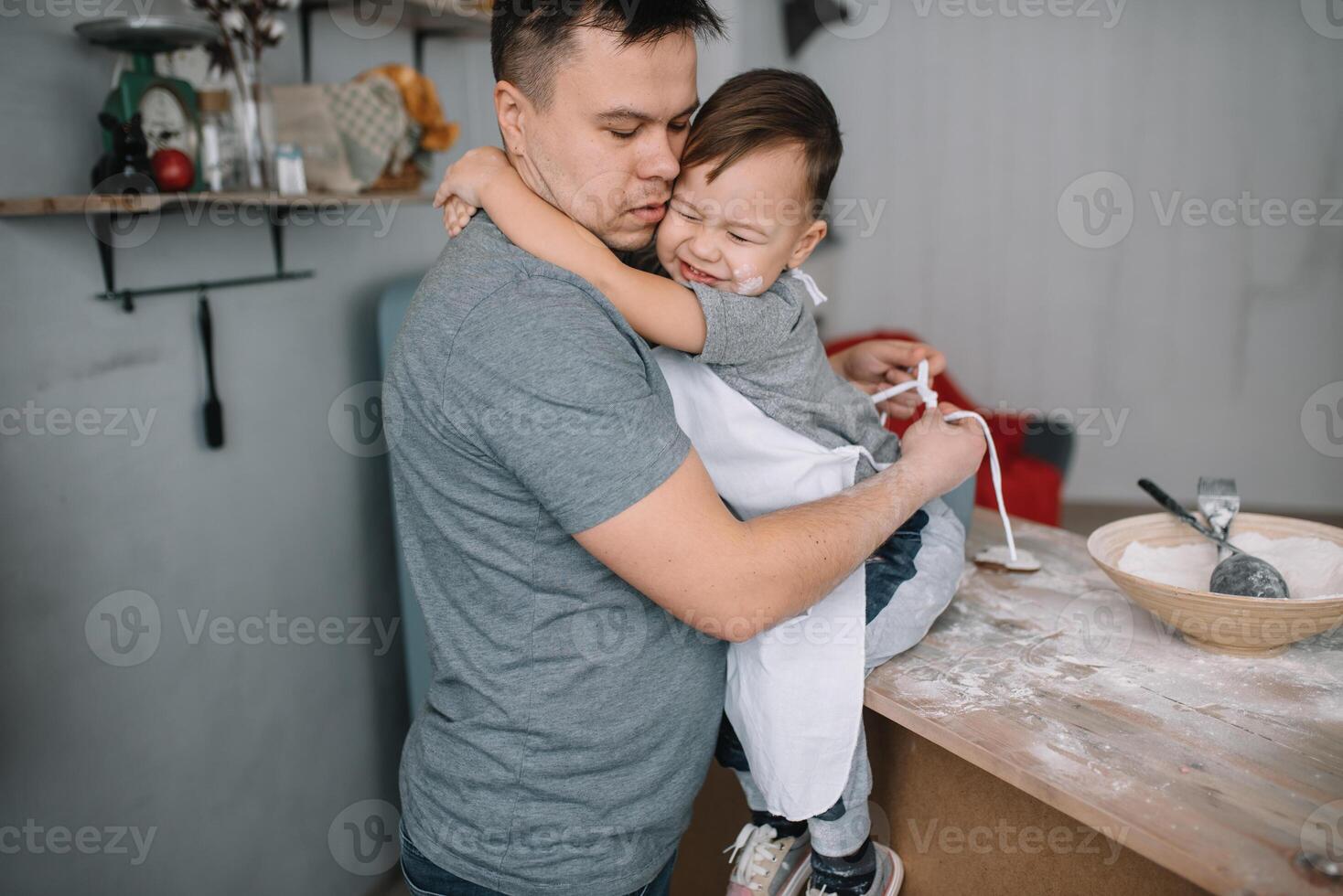 Young man and his son with oven sheet in kitchen. Father with little son on the kitchen. photo