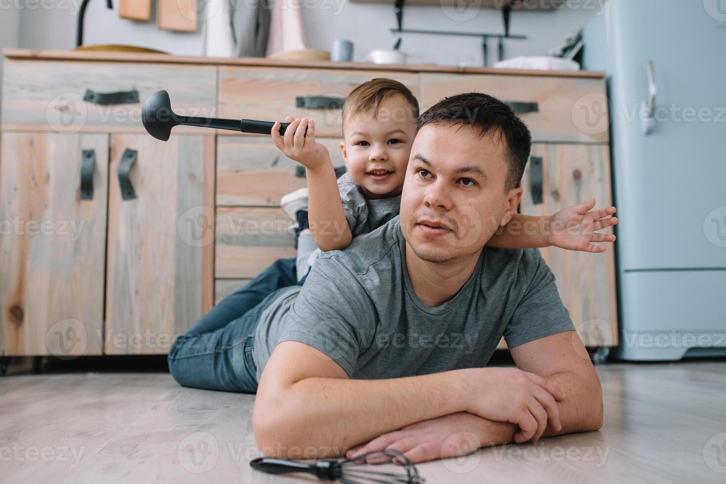 Young man and his son with oven sheet in kitchen. Father with little son on the kitchen photo
