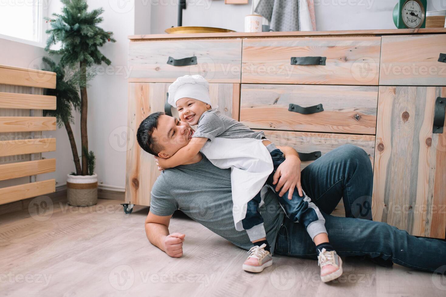 Young man and his son with oven sheet in kitchen. Father with little son on the kitchen. photo