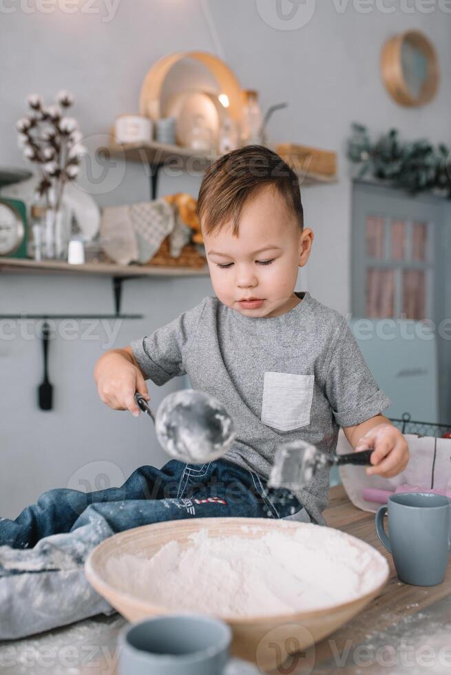 joven chico linda en el cocina cocinar cocinero en blanco uniforme y sombrero cerca mesa. hecho en casa pan de jengibre. el chico cocido el chocolate galletas. foto