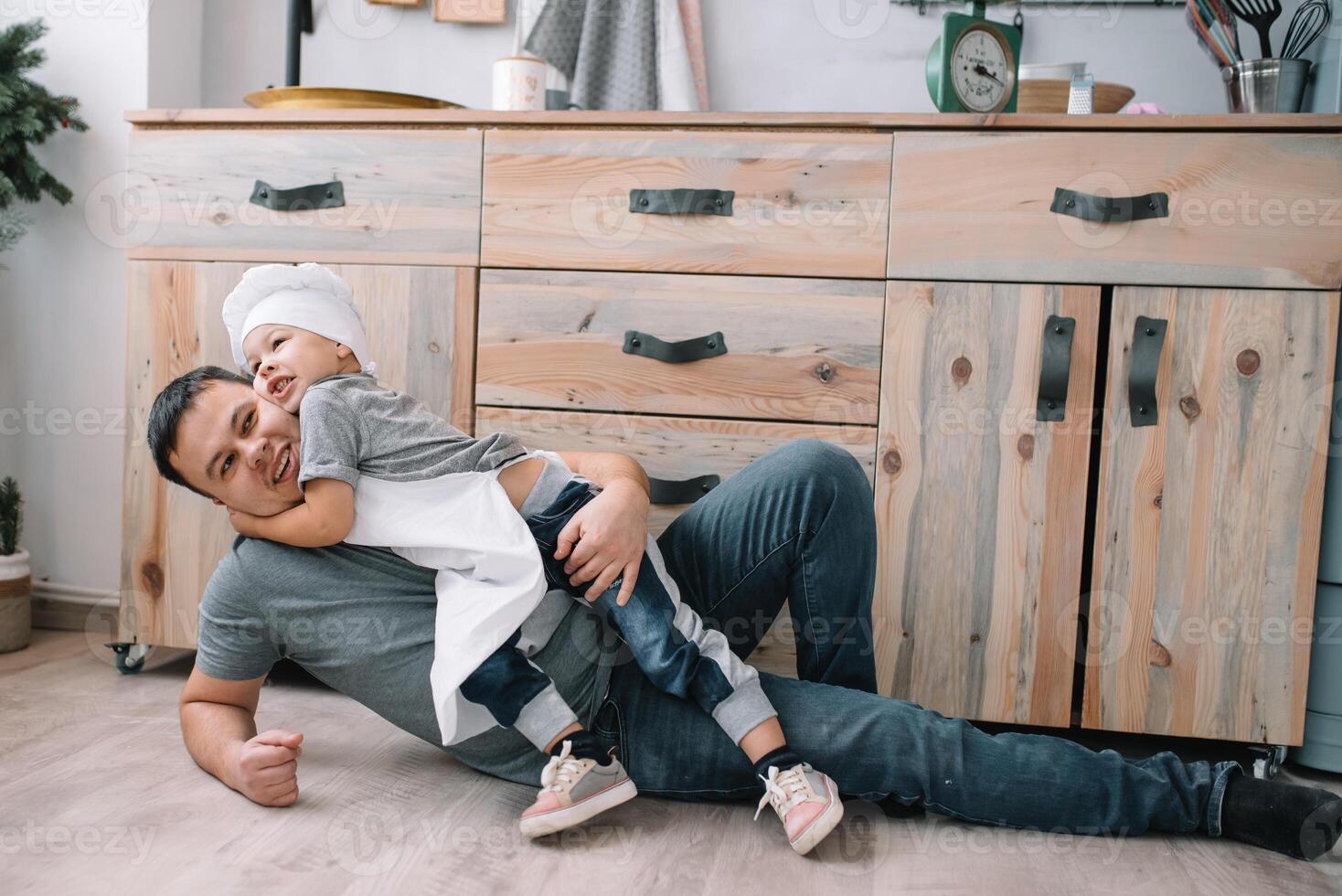 Young man and his son with oven sheet in kitchen. Father with little son on the kitchen. photo