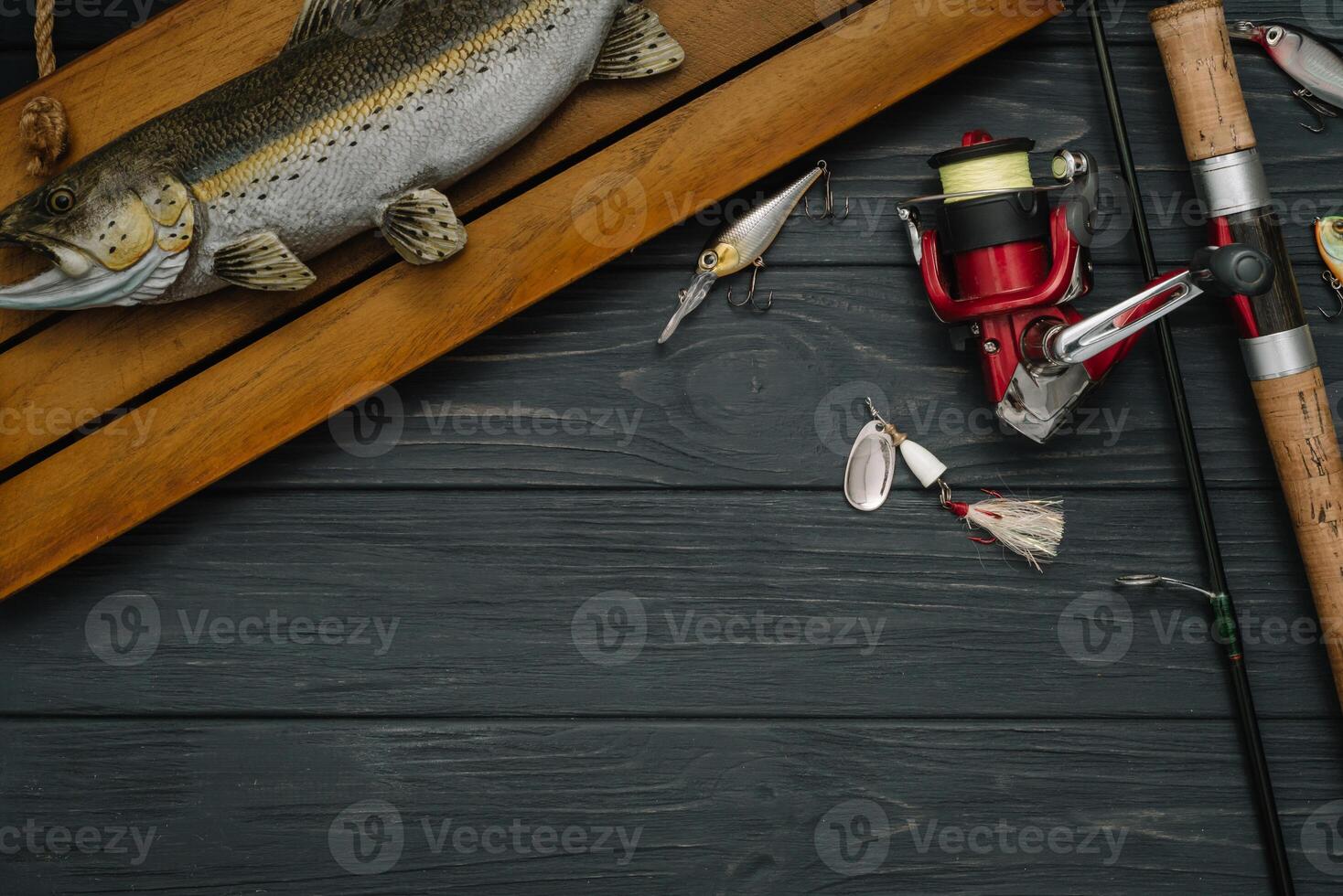 Fishing tackle - fishing spinning, hooks and lures on darken wooden background. Top view photo