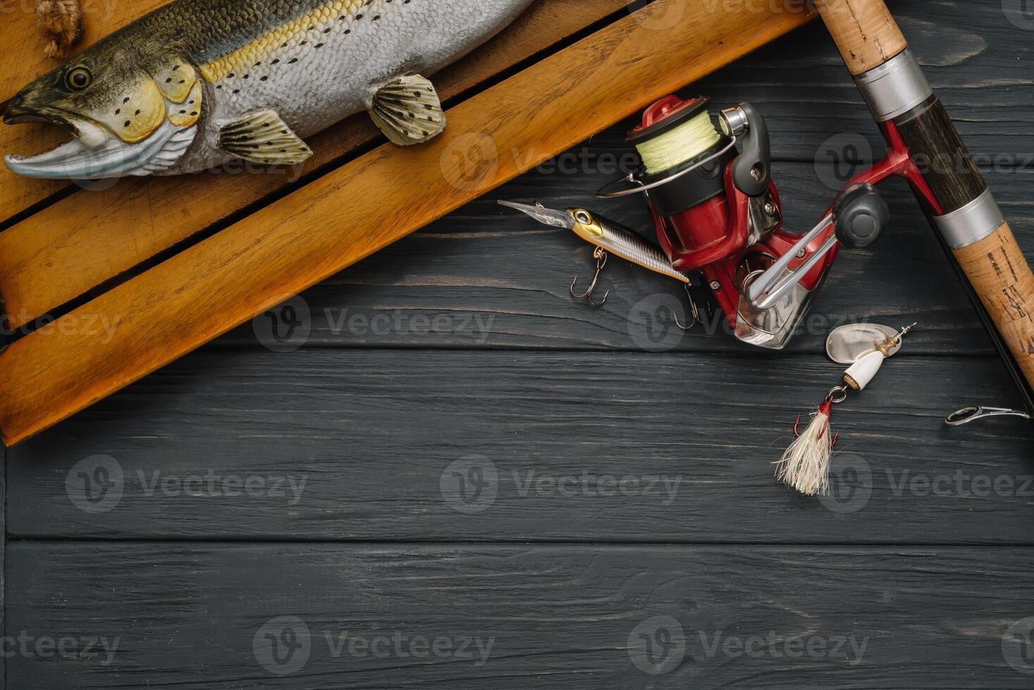 Fishing tackle - fishing spinning, hooks and lures on darken wooden background. Top view. photo