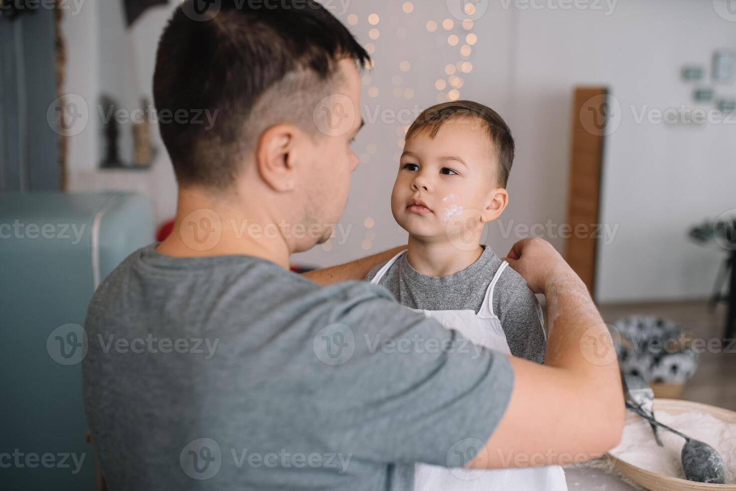 Young man and his son with oven sheet in kitchen. Father with little son on the kitchen. photo