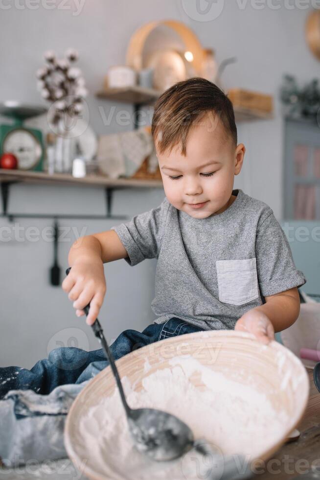 joven chico linda en el cocina cocinar cocinero en blanco uniforme y sombrero cerca mesa. hecho en casa pan de jengibre. el chico cocido el chocolate galletas. foto