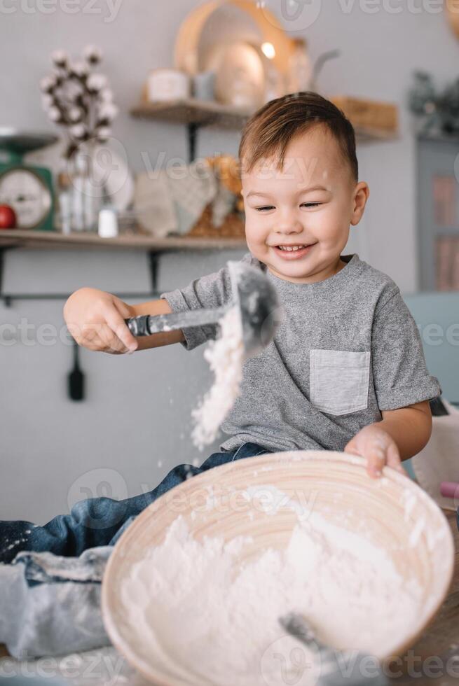 joven chico linda en el cocina cocinar cocinero en blanco uniforme y sombrero cerca mesa. hecho en casa pan de jengibre. el chico cocido el chocolate galletas. foto