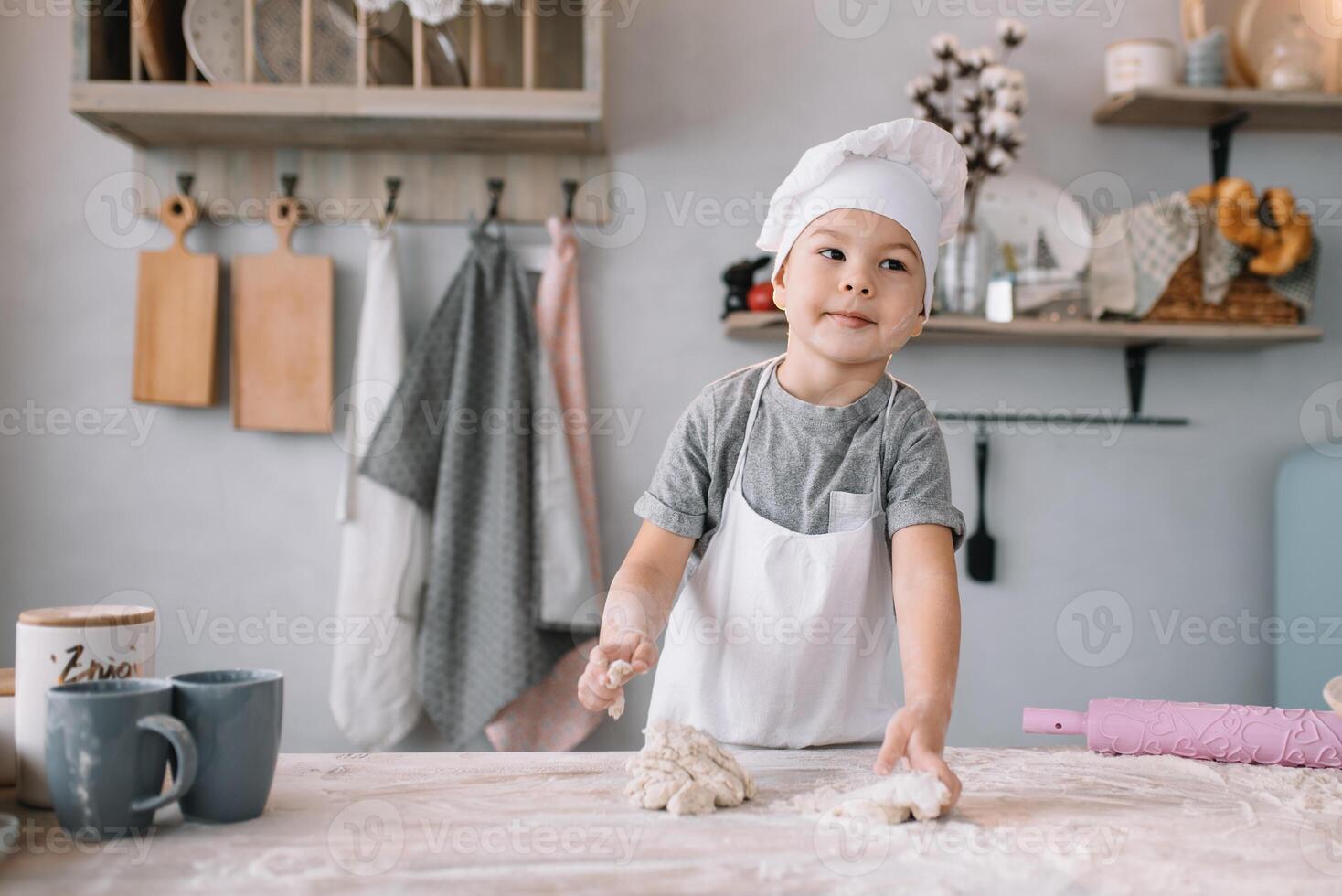 Young boy cute on the kitchen cook chef in white uniform and hat near table. homemade gingerbread. the boy cooked the chocolate cookies. photo