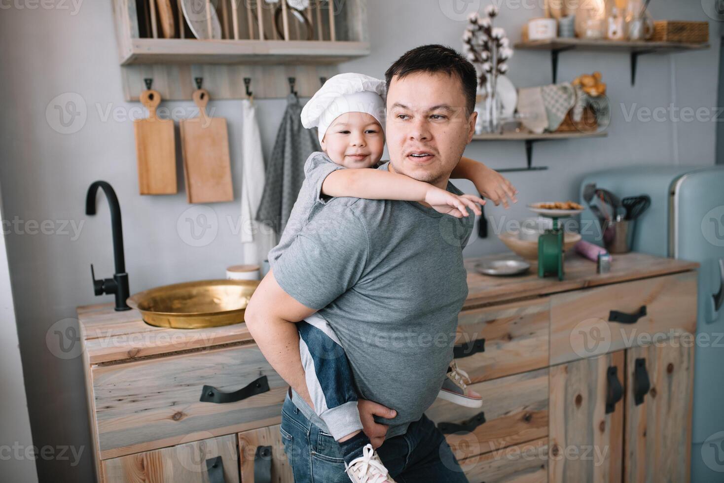 Young man and his son with oven sheet in kitchen. Father with little son on the kitchen. photo