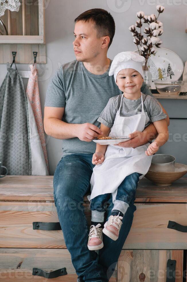 Young man and his son with oven sheet in kitchen. Father with little son on the kitchen photo