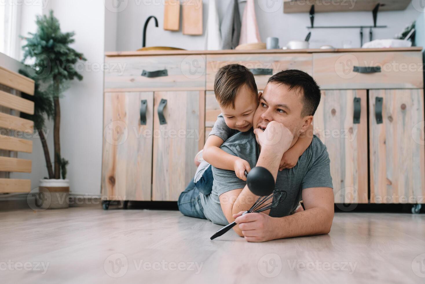 Young man and his son with oven sheet in kitchen. Father with little son on the kitchen photo