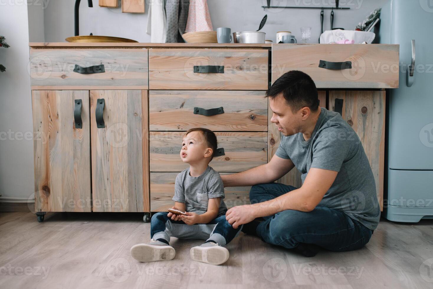 Young man and his son with oven sheet in kitchen. Father with little son on the kitchen photo