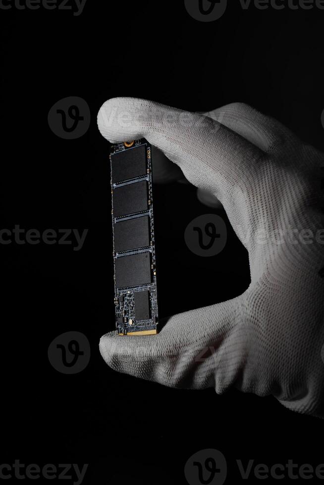 In the Darkness Hand Securely Grasping High-Speed M.2 SSD for PC photo