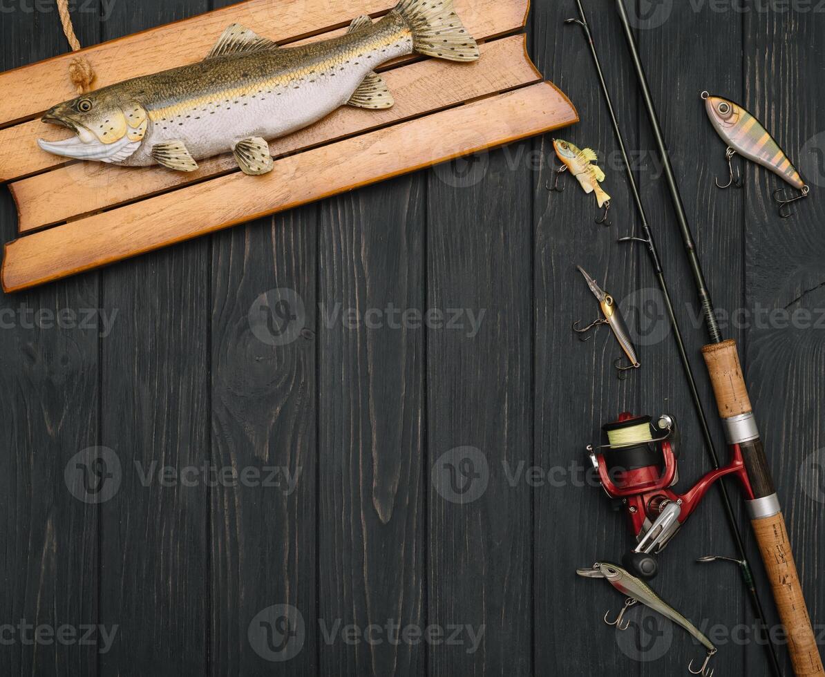 Fishing tackle - fishing spinning, hooks and lures on darken wooden background. Top view photo