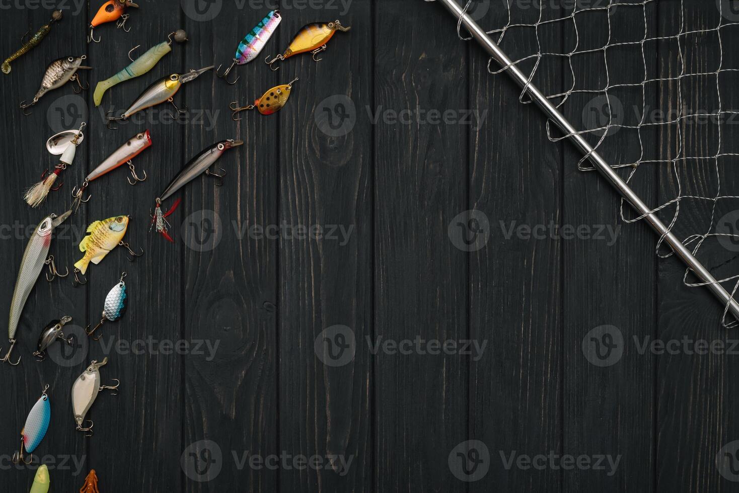 Fishing tackle - fishing spinning, hooks and lures on darken wooden background. Top view photo