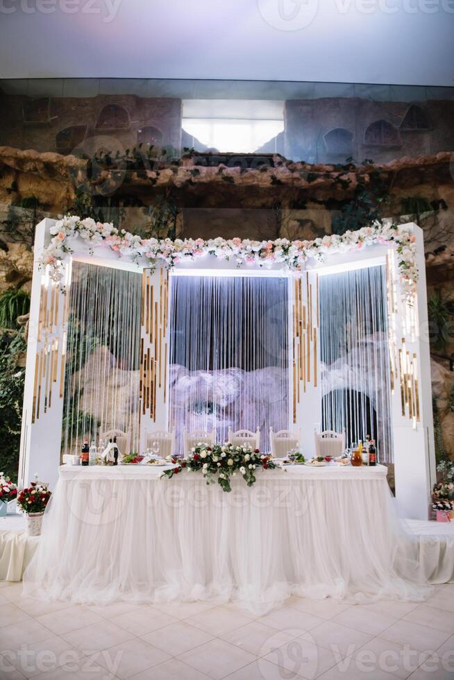 wedding decor - spring flowers and eucalyptus branches, candle cans and purple fabric in the wedding arch on the background of green grass and the river. photo