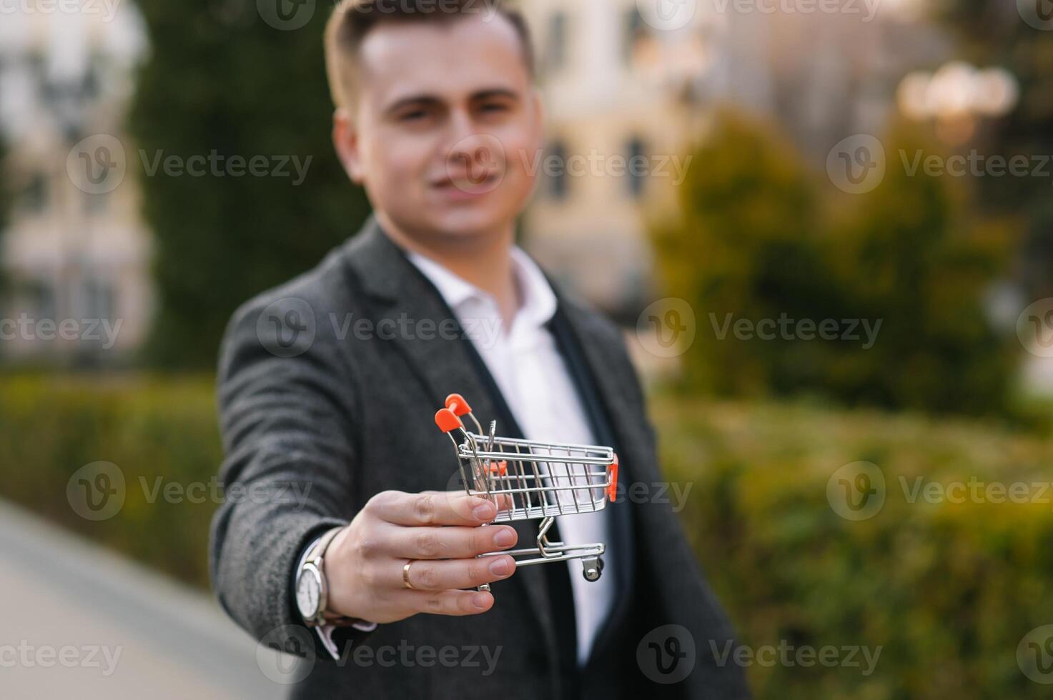 Grocery store chain management, retailing and daily consumer goods trade concept. Business man in a suit with a small miniature shopping cart photo