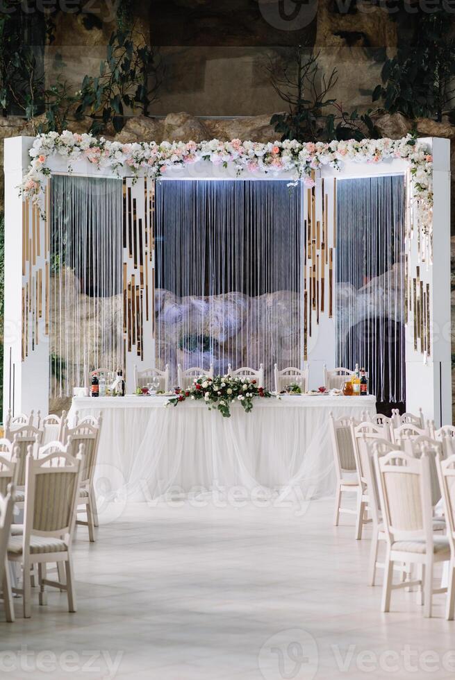 wedding decor - spring flowers and eucalyptus branches, candle cans and purple fabric in the wedding arch on the background of green grass and the river. photo