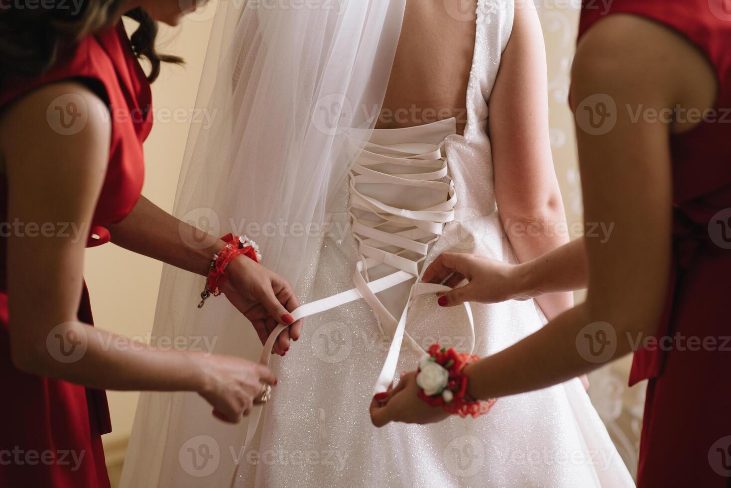 Bridesmaid preparing bride for wedding day. Bridesmaid helping bride fasten lacing her wedding white dress before ceremony. Luxury bridal dress close up. Wedding morning moments details concept. photo