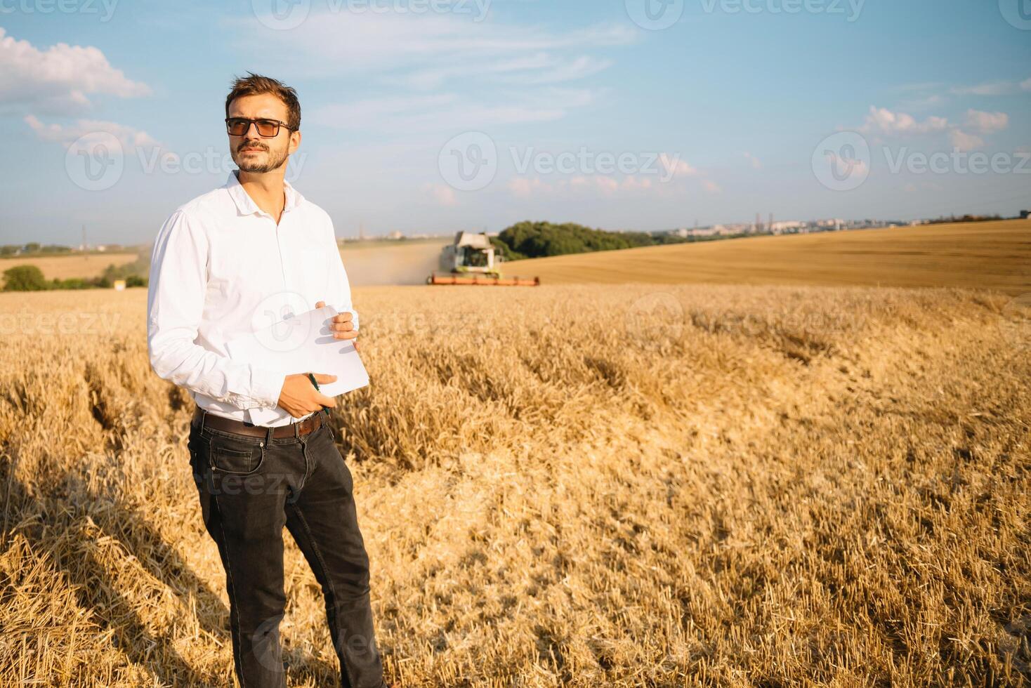 Happy farmer in the field checking corn plants during a sunny summer day, agriculture and food production concept photo