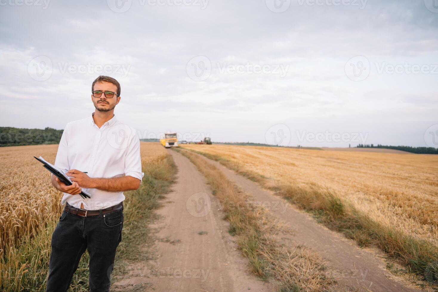 young farmer engineer standing on wheat field photo