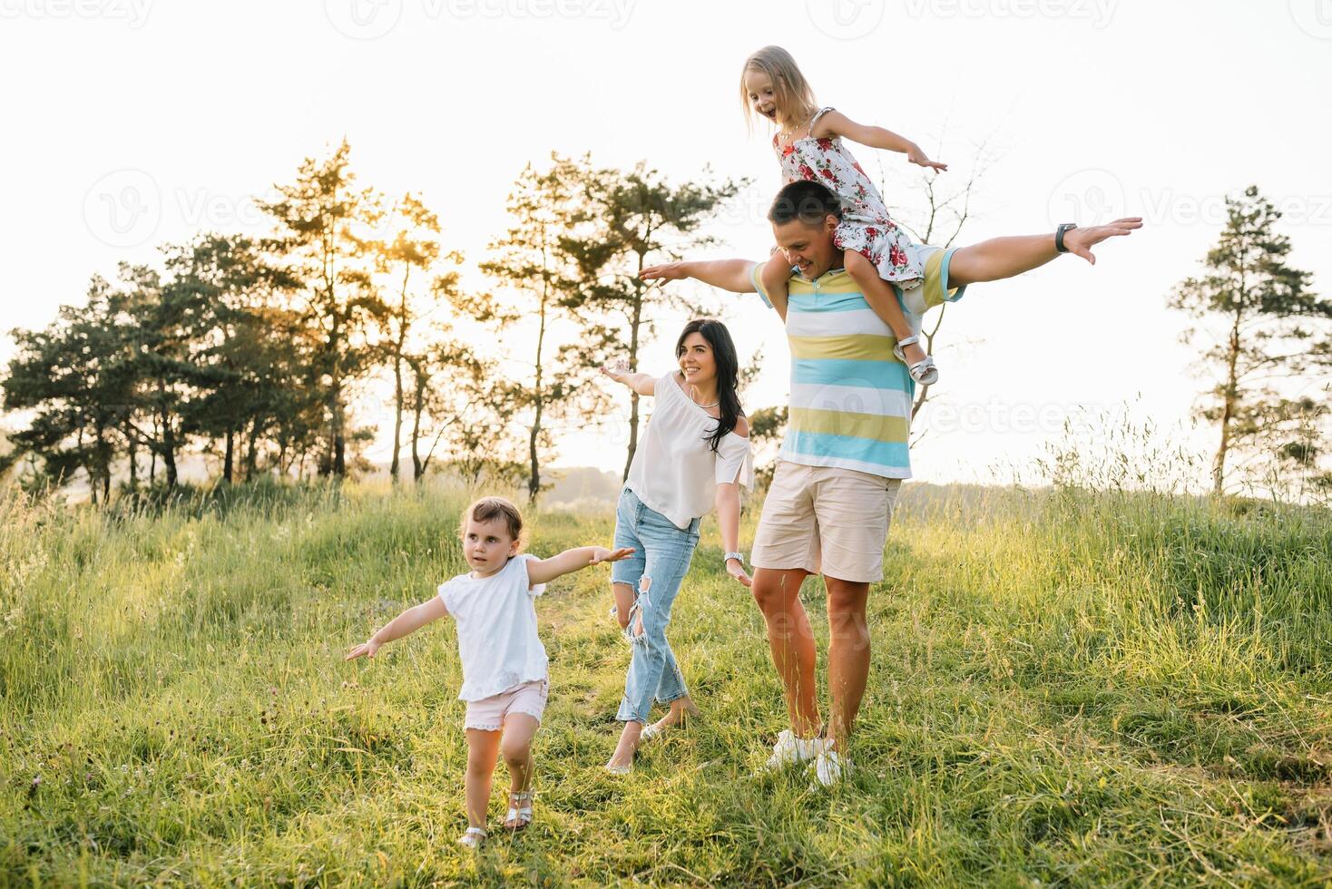 color foto de sonriente joven padres y dos niños, descanso y tener divertido en naturaleza. amar, familia y contento infancia estilo de vida concepto.