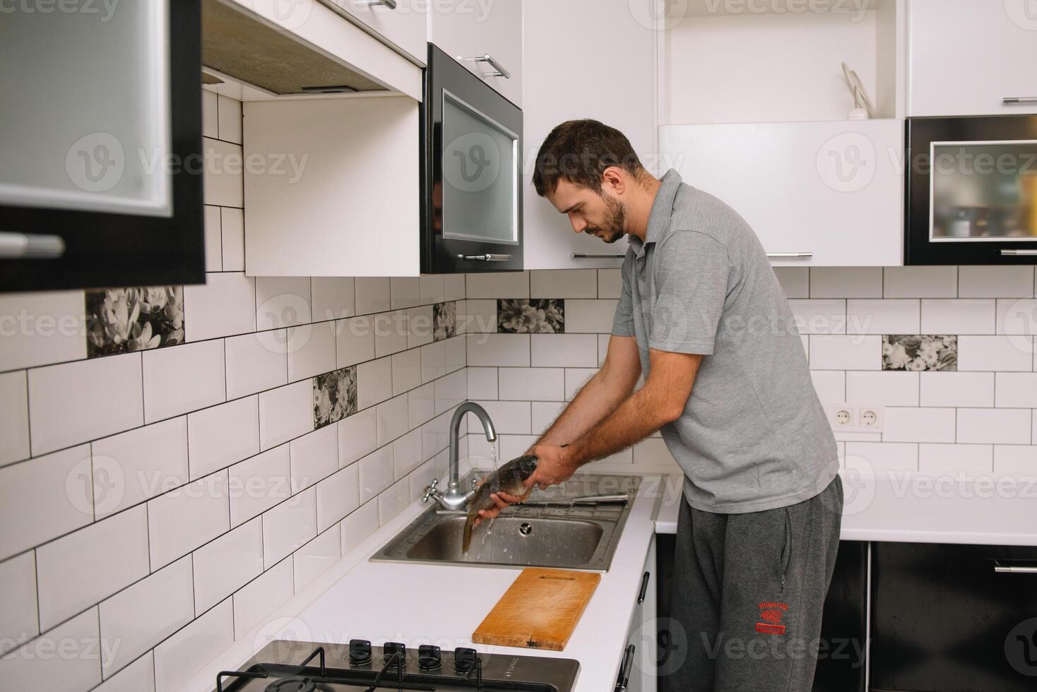 Man cutting fresh fish in kitchen in home. Man butchering fish for cook. photo