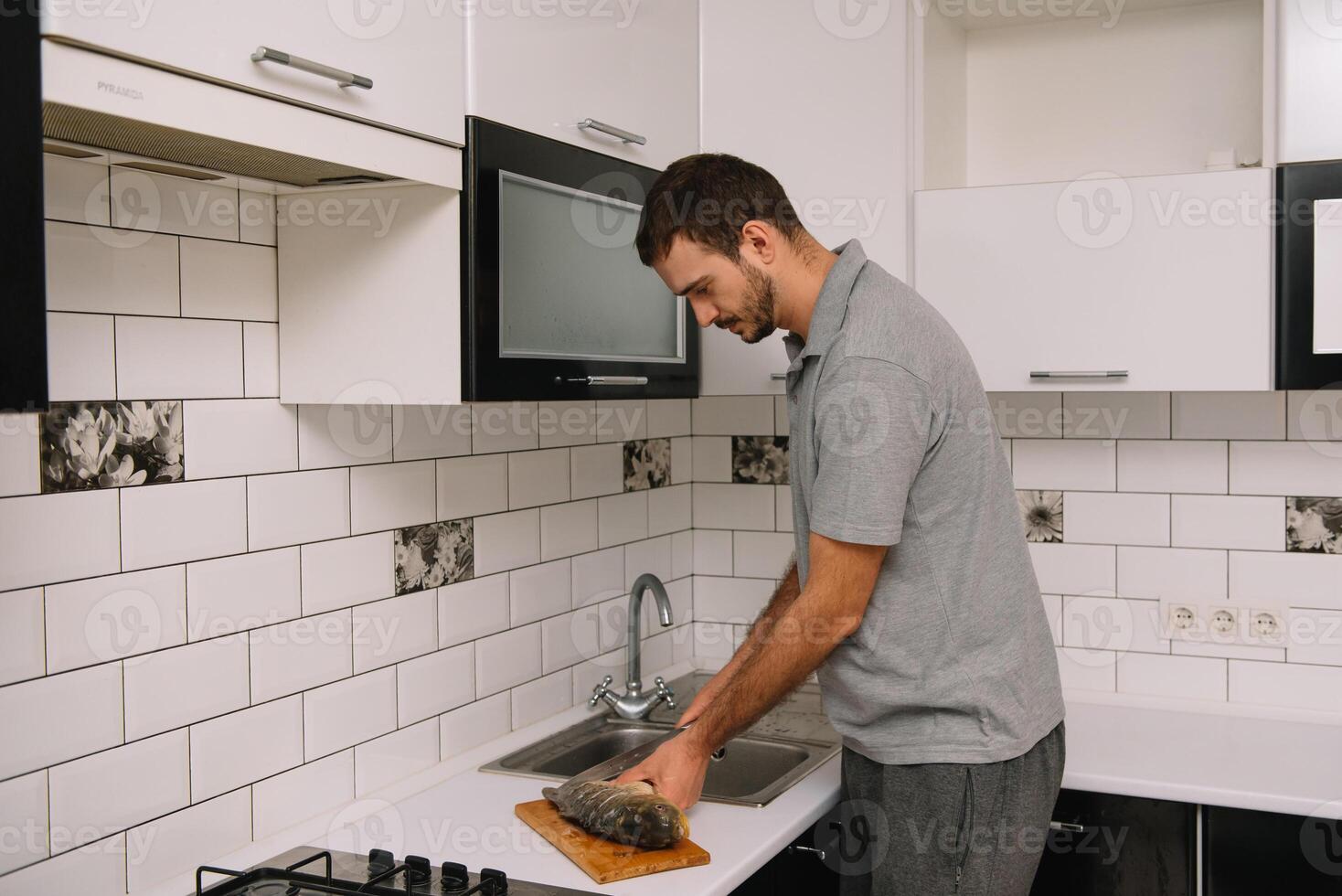 Man cutting fresh fish in kitchen in home. Man butchering fish for cook. photo