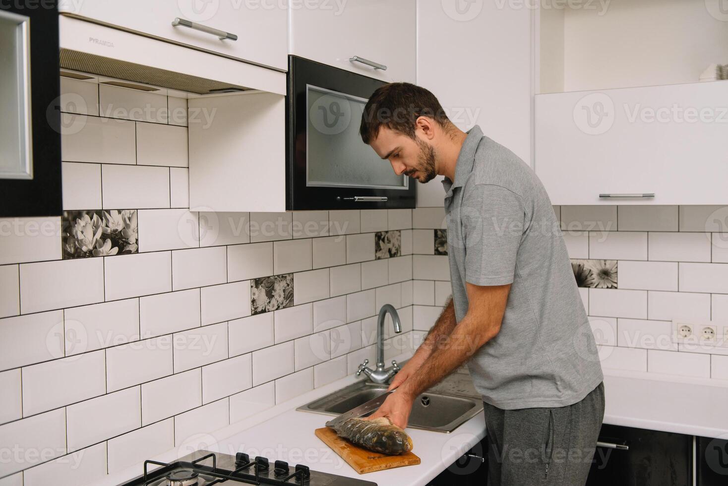 Man cutting fresh fish in kitchen in home. Man butchering fish for cook. photo