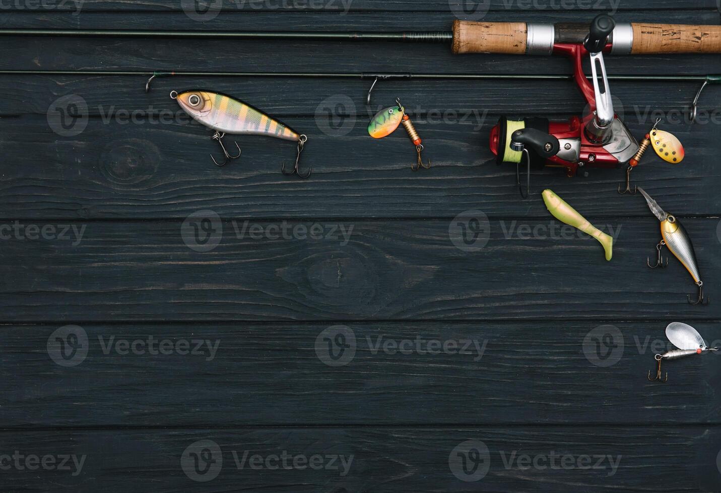 Fishing tackle - fishing spinning, hooks and lures on darken wooden background. Top view photo