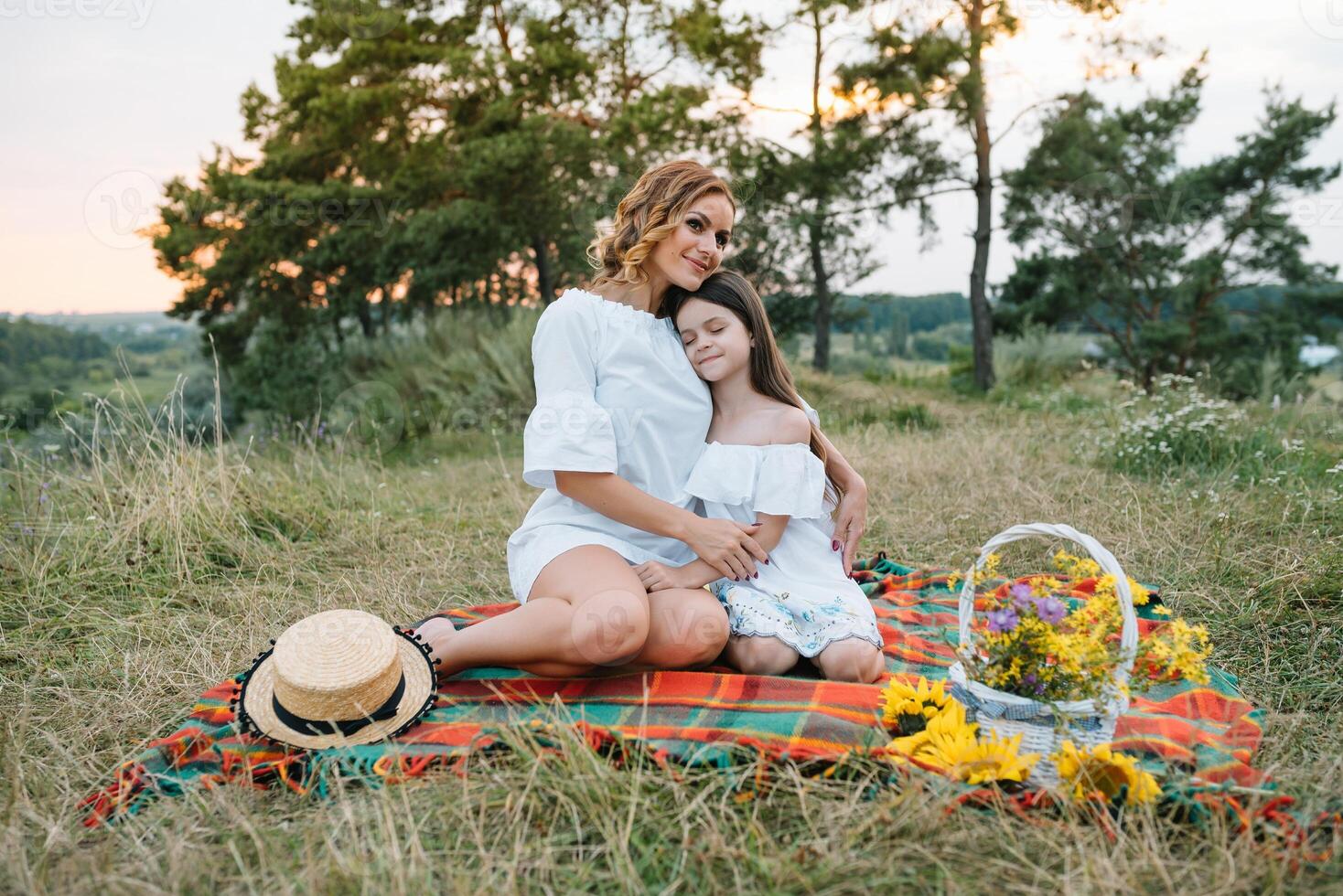 Cheerful mother and her little daughter having fun together in the summer background. Happy family in the nature background. Cute girls with colorful flowers. photo