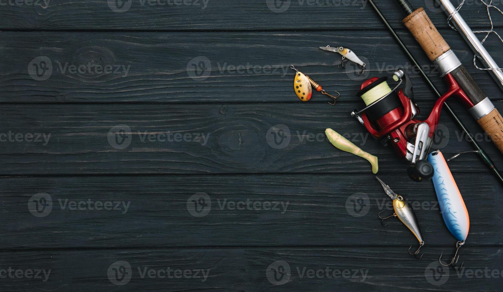 Fishing tackle - fishing spinning, hooks and lures on darken wooden background. Top view photo