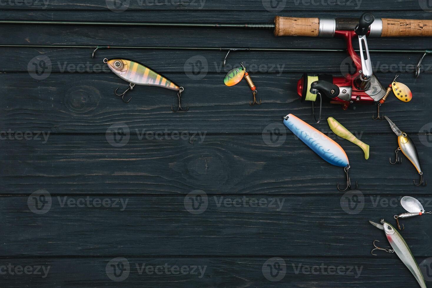 Fishing tackle - fishing spinning, hooks and lures on darken wooden background. Top view photo