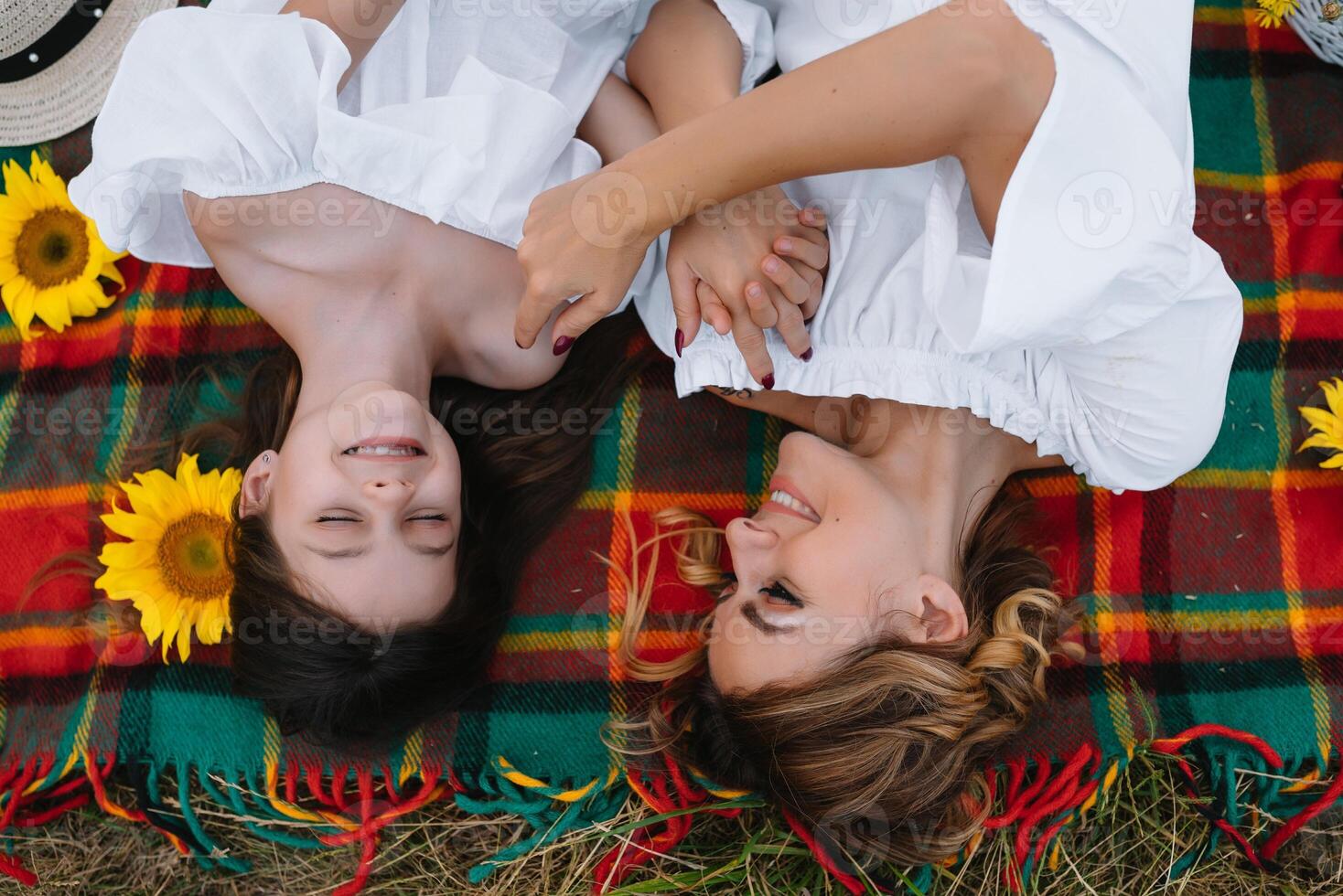 Top view of happy woman smiling and playing with her cute little child, lying outdoor.Loving mother and daughter spend time together in a park. Mom and kid has fun. Mother's day photo