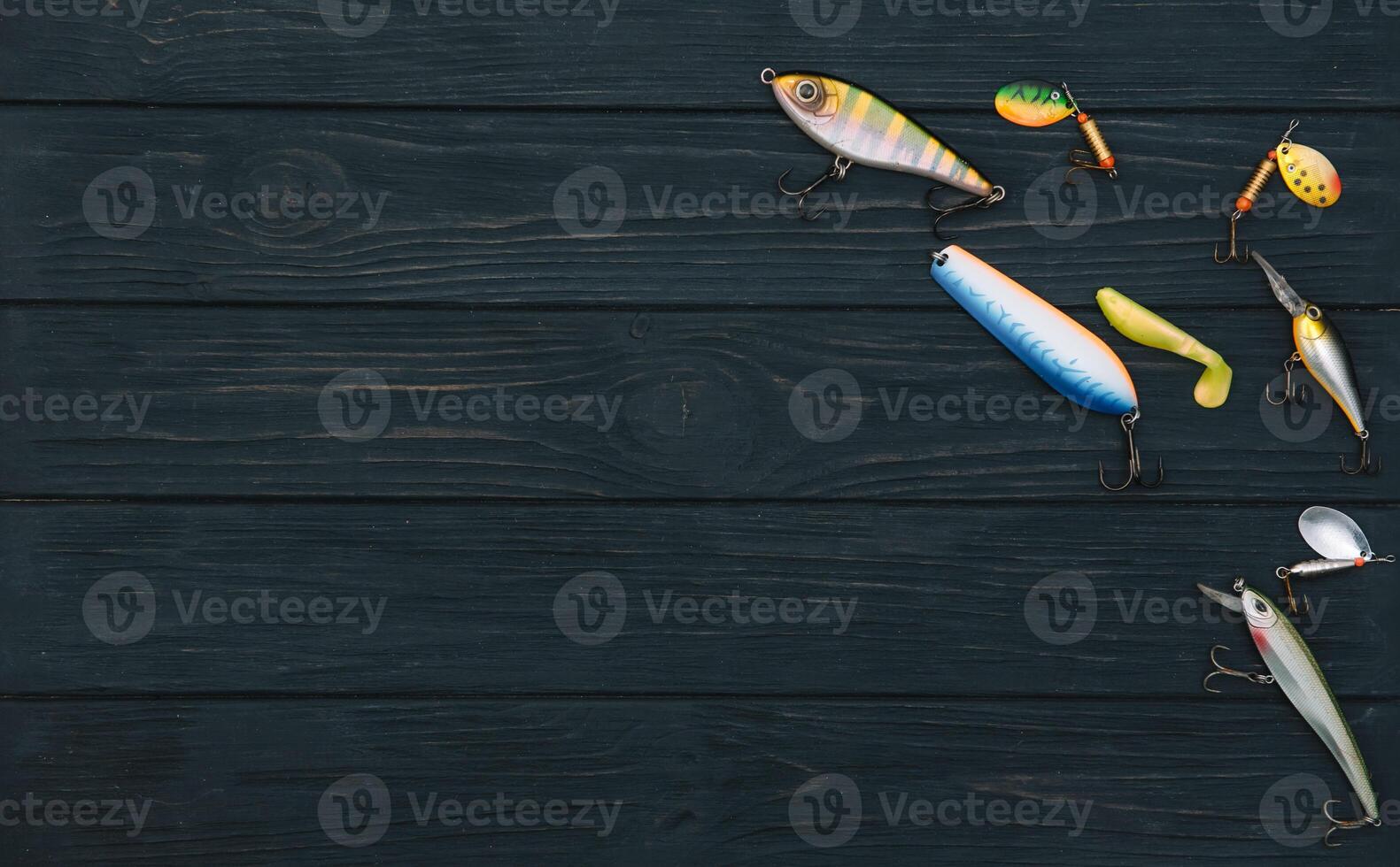 Fishing tackle - fishing spinning, hooks and lures on darken wooden background. Top view photo